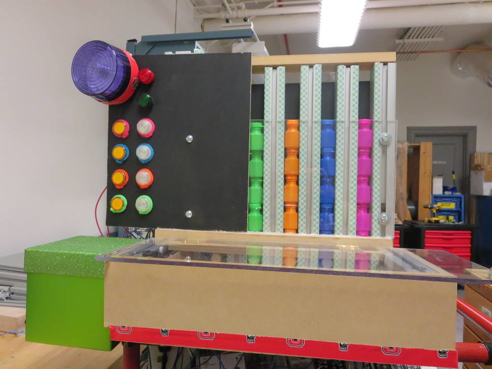 View of front of system, showing the box for coin collection, the product inventory (bottles of bubble solution), buttons and lights color-coded to individual products, and other system indicator lights.